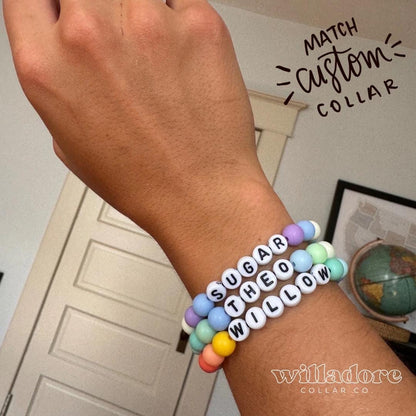 Wrist wearing pastel beaded name bracelets reading SUGAR, THEO, and WILLOW, showing matching accessory options for Willadore Collar Co.’s personalized beaded dog collars