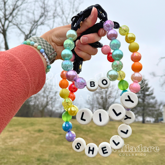 Three personalized beaded dog collars featuring multicolor beads and custom name letters held in a hand outdoors, handcrafted by Willadore Collar Co