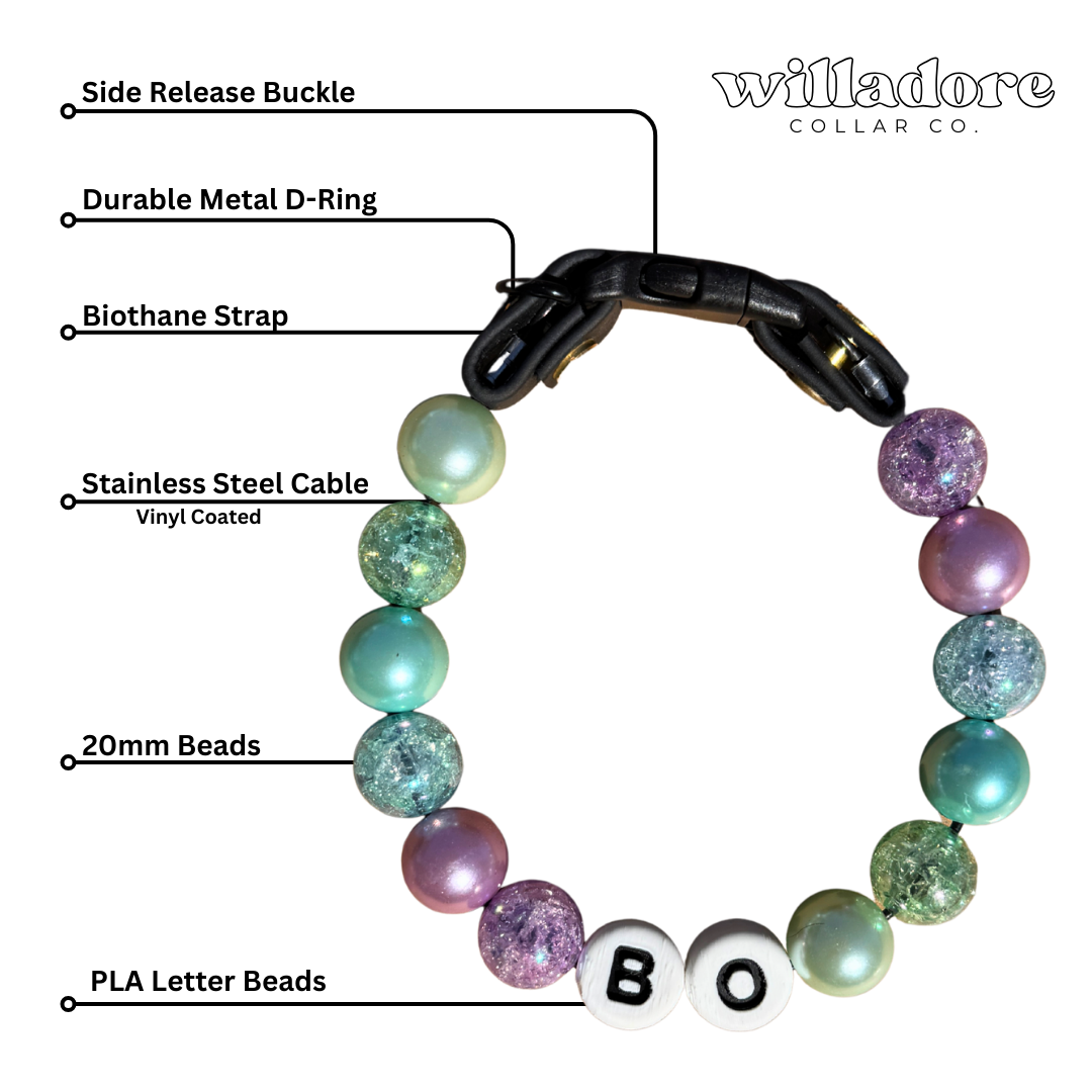 Labeled diagram of a custom beaded dog collar showing the side‑release buckle, metal D‑ring, Biothane strap, stainless steel cable, 20mm beads, and PLA letter beads in purple, teal, green, and pearl colors, illustrating the construction and customization options for Willadore Collar Co.’s handmade personalized beaded dog collars